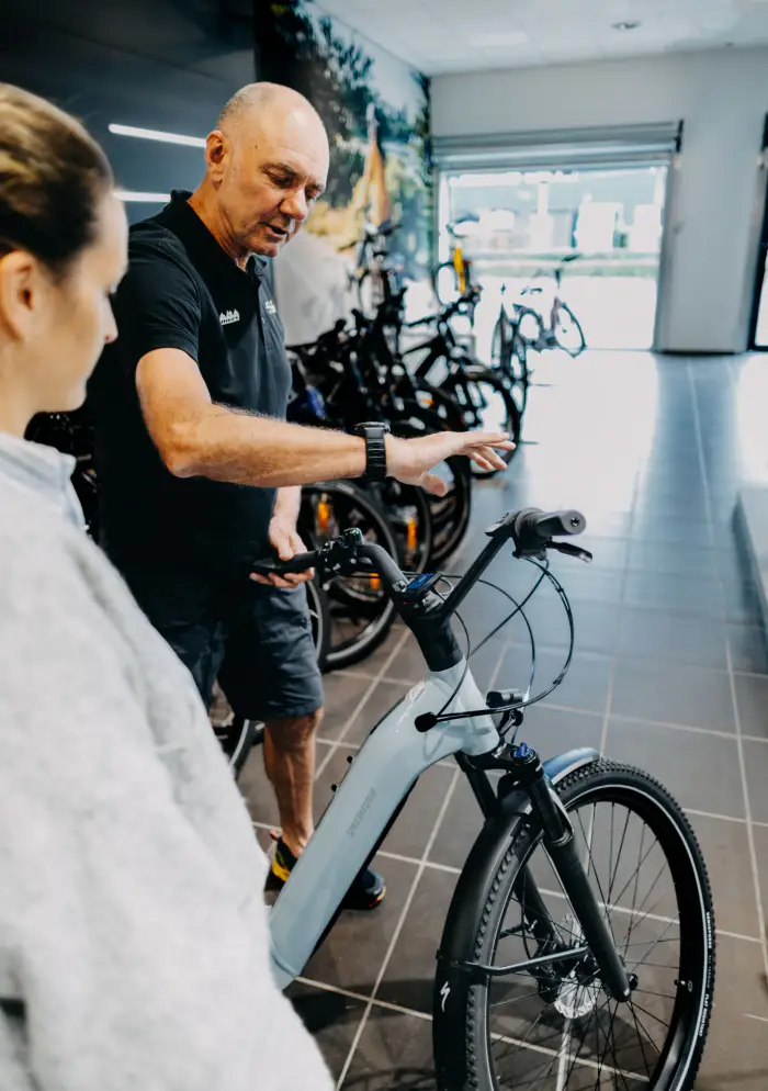 Medewerker van URBN Bikes geeft uitleg over een e-bike in de winkel